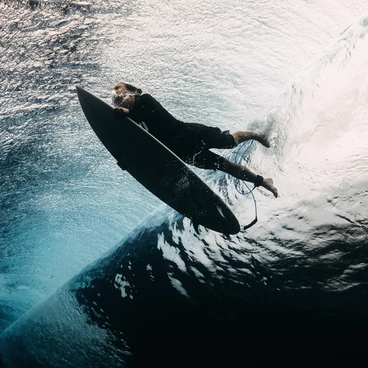 Surfer duck diving under a wave, seen from below